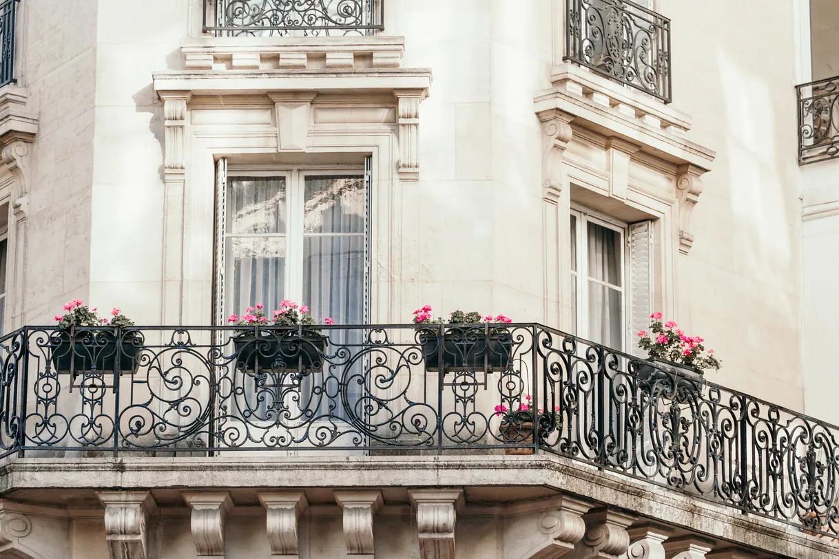 Élégant bâtiment parisien, balcons en fer forgé fleuris de roses.