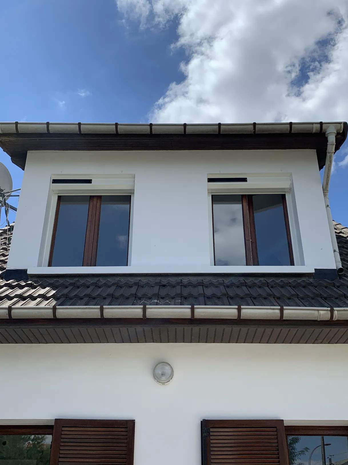 Fenêtres de toit sur une façade blanche avec un ciel bleu.