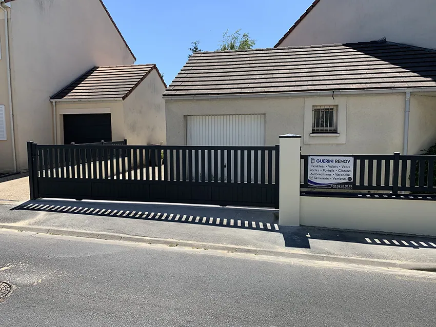 Grand portail coulissant noir et clôture devant une maison résidentielle PORTAILS ET CLÔTURES