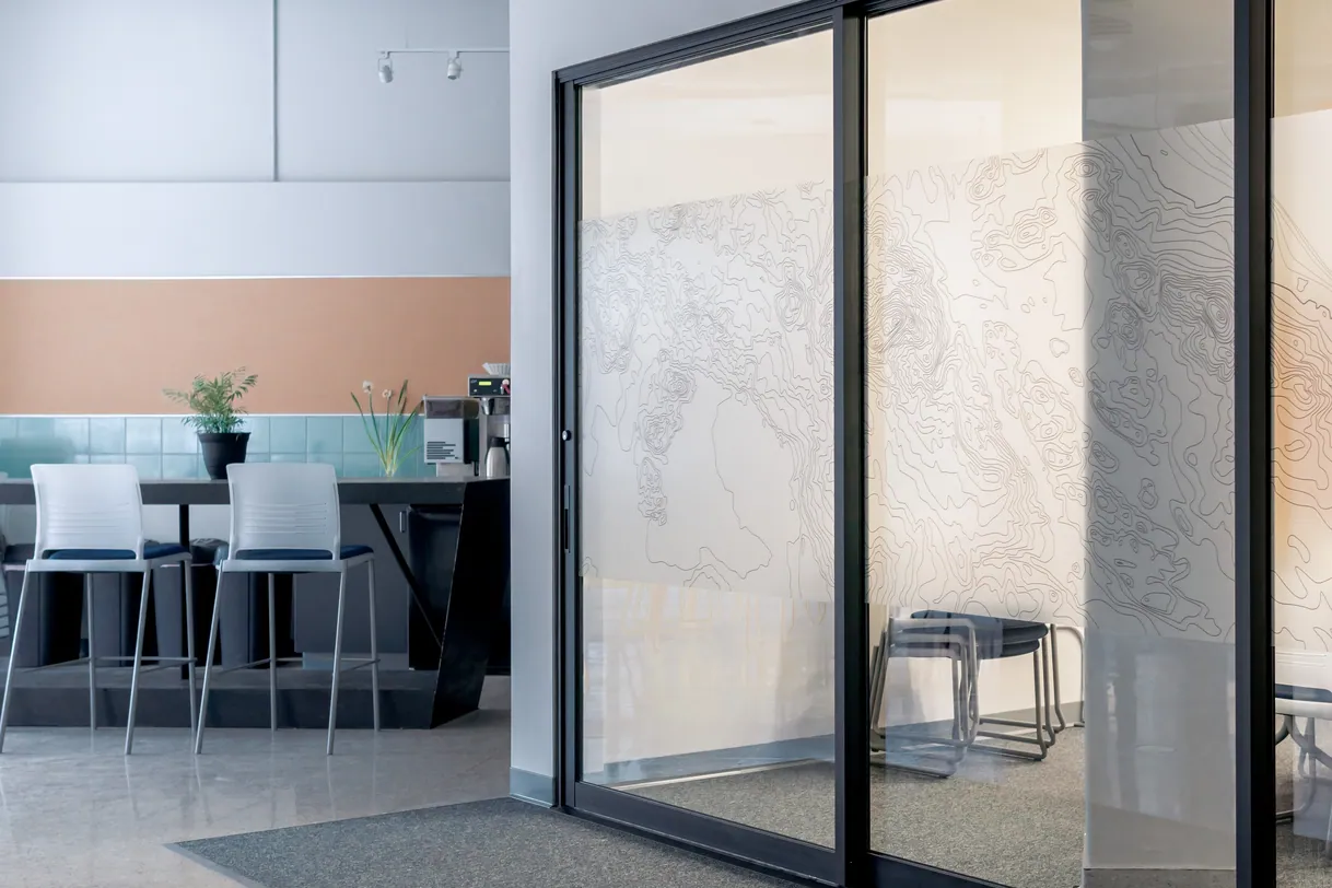 Grande porte coulissante en verre noir, cuisine moderne en arrière-plan.