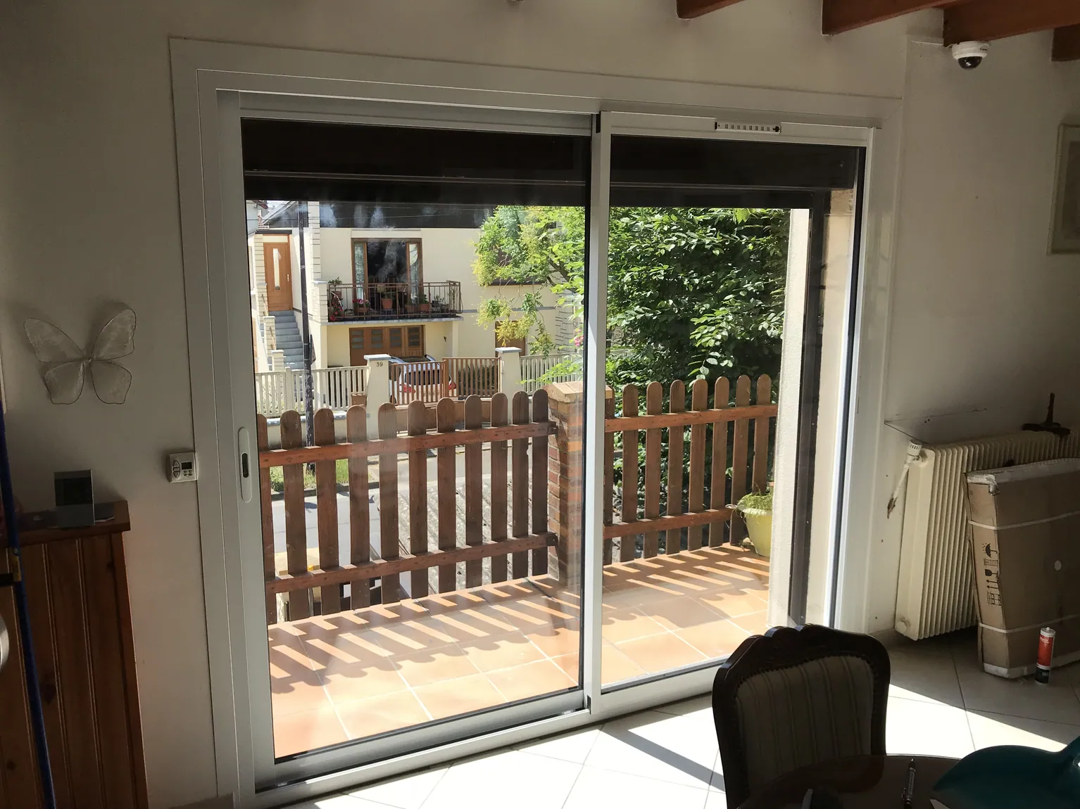 Grande porte coulissante vitrée donnant sur une terrasse avec clôture bois.