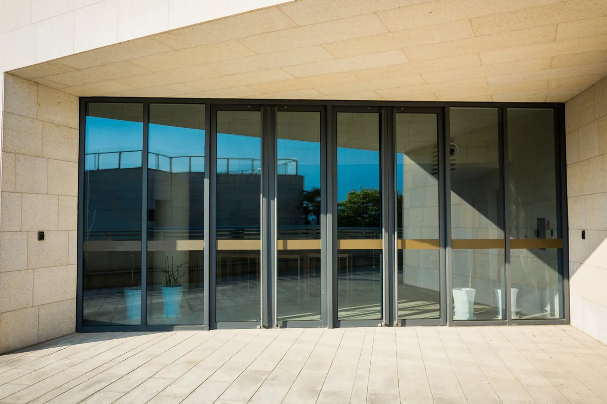Grandes portes vitrées modernes reflétant le ciel d'un bâtiment contemporain.
