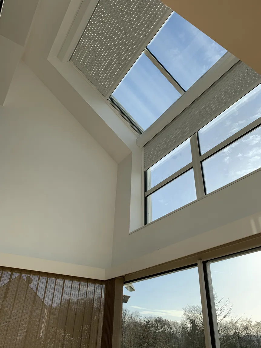 Intérieur moderne lumineux avec haut plafond, grandes fenêtres et puits de lumière.