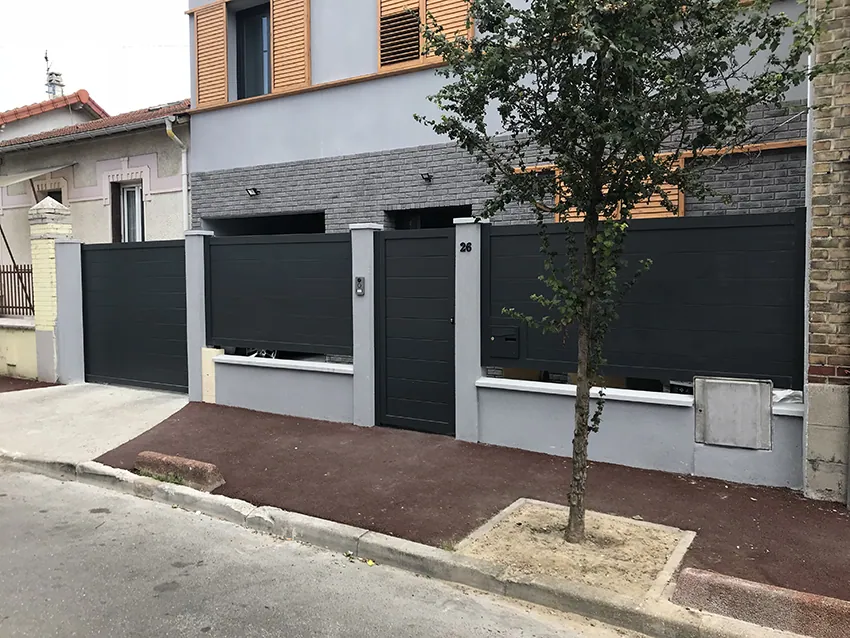 Maison moderne avec clôture et portail gris anthracite dans quartier résidentiel.