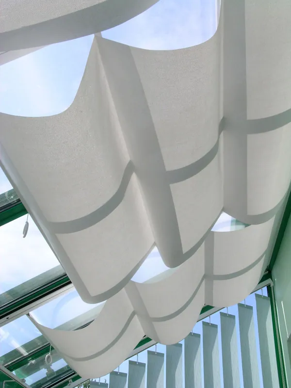 Plafonnier moderne avec des panneaux blancs ondulés et un design architectural.