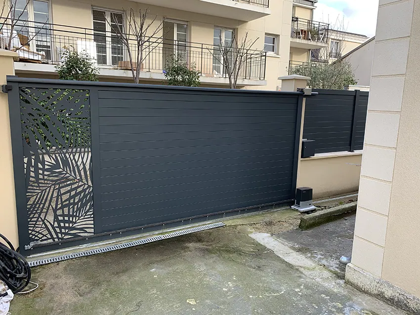 Portail coulissant moderne gris foncé avec motifs végétaux découpés au laser.