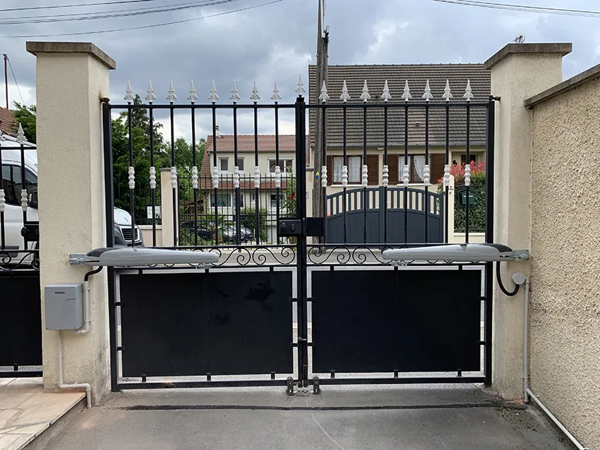 Portail d'entrée métallique noir avec bras automatiques et piliers.