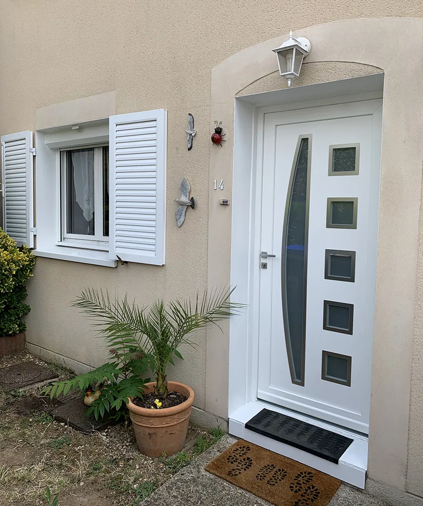Porte d'entrée blanche moderne, fenêtre avec volets blancs et plante en pot.