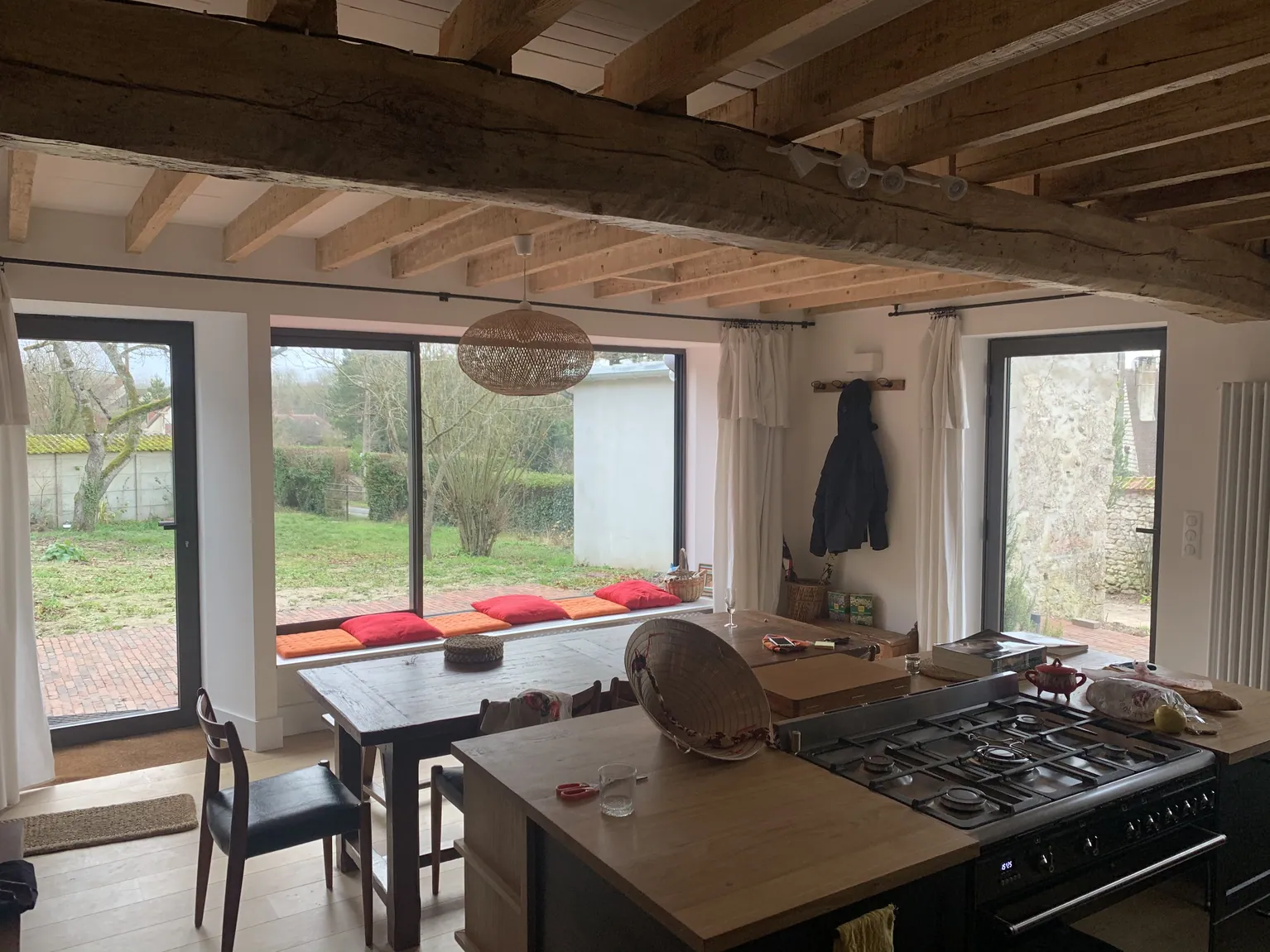 Cuisine-salle à manger rustique avec fenêtres panoramiques et poutres apparentes.